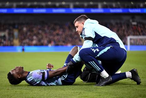 Bukayo Saka of Arsenal receives medical attention on the field.