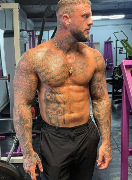 Ross McCarthy, shirtless and tattooed, in a gym.