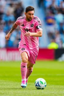 Lionel Messi in pink Inter Miami uniform dribbling a soccer ball.