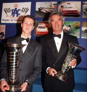 Michael Schumacher and Flavio Briatore holding Formula 1 World Championship awards.