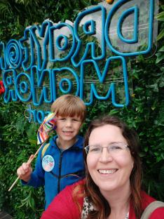 A young boy and a woman pose in front of a blue
