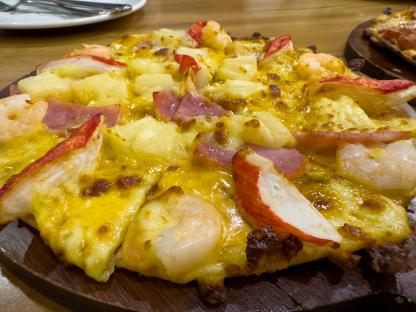 Seafood pizza on a wooden tray.