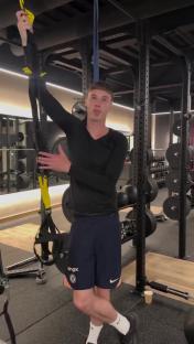 Man in gym demonstrating a TRX exercise.