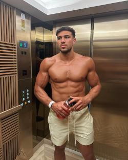 Tommy Fury in an elevator, shirtless, holding a water bottle.