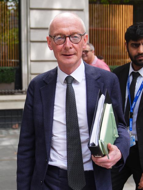 A man in a suit and tie wearing a lanyard that says 'BBC'