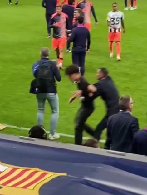 A pitch invader being tackled by security personnel on a soccer field.