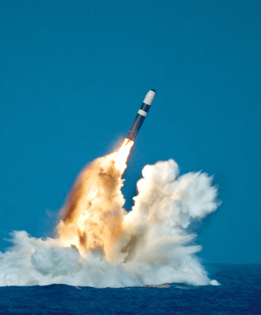 A missile launching from the ocean with a large plume of smoke and fire.