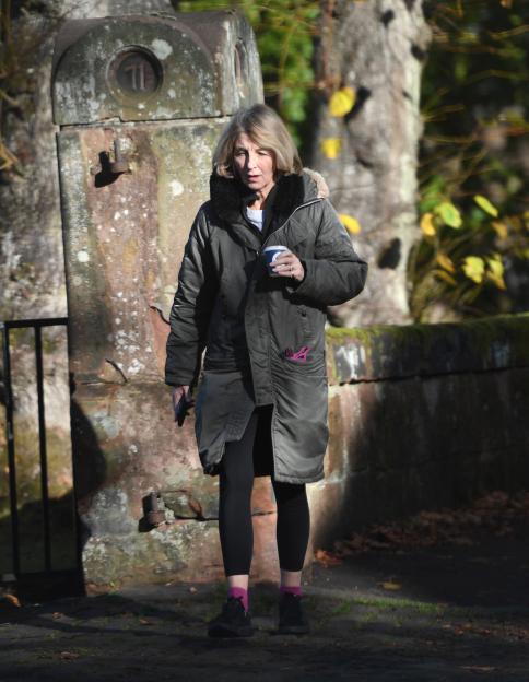 Kaye Adams walking while holding a coffee cup.