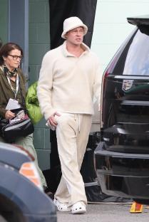 Brad Pitt wearing white Crocs on the set of a film.