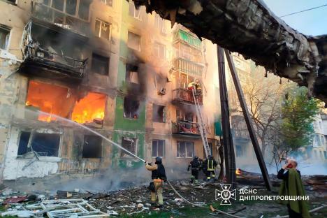 Ukrainian rescuers evacuate a woman from a burning building after a drone attack.