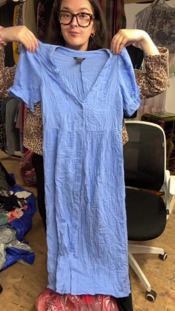 Woman holding up a light blue dress.