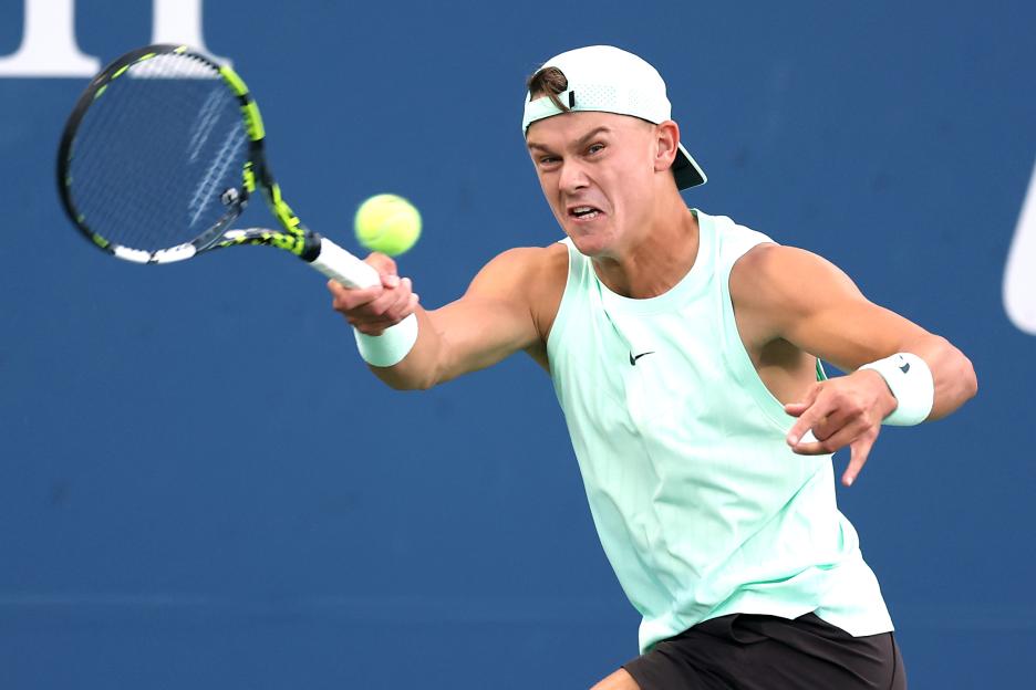 Holger Rune of Denmark returning a tennis serve.