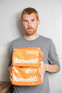 Man holding two loaves of Warburton's bread.