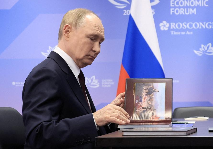 Russia's President Vladimir Putin looks down at a book he is holding.