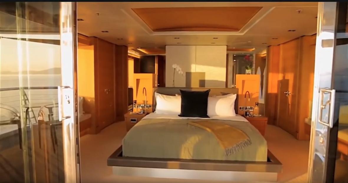 Interior of a luxurious yacht bedroom with a balcony overlooking the sea.