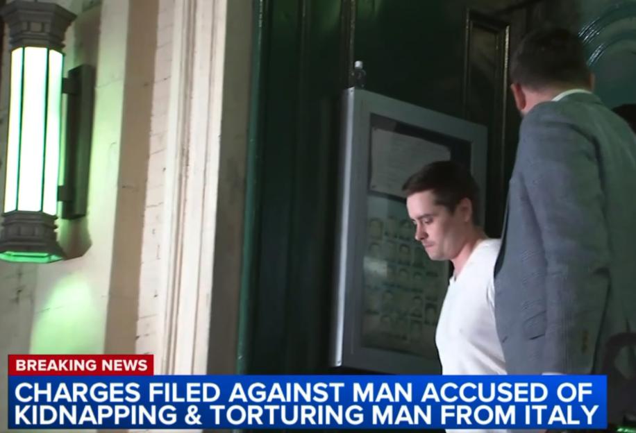 A man accused of kidnapping and torturing an Italian man is led away in handcuffs.