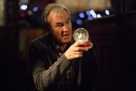 Larry Lamb holding a snow globe.