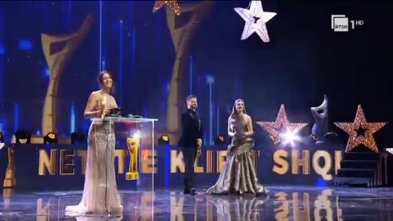 Award ceremony with two women in gowns accepting awards.