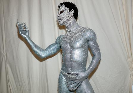 Person in silver glitter body paint and jeweled adornments at the Met Gala.