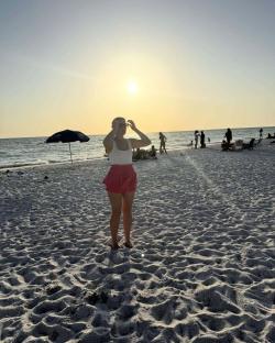 Woman in pink skirt on beach at sunset.