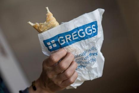 A partially eaten Gregg's sausage roll in a crumpled paper bag.