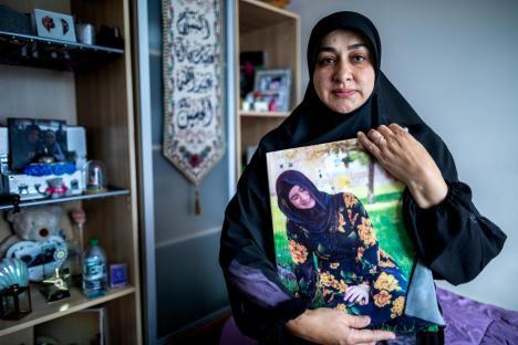 Woman in hijab holding a photo of her deceased daughter.