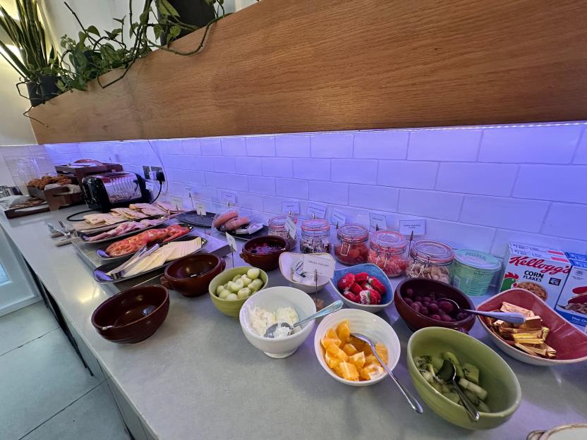 Breakfast buffet with a variety of foods including fruit, cereals, yogurts, pastries, and cold cuts.