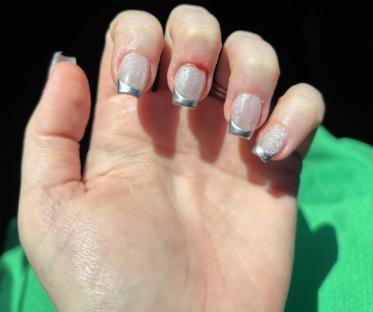 Hand with a silver glitter French manicure.