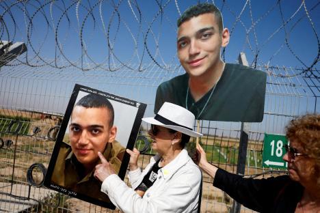 A grandmother holds photos of her kidnapped grandson near a border fence.