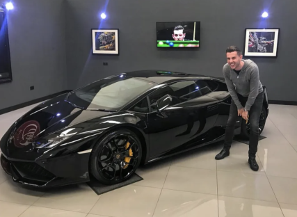 Man crouching beside a black Lamborghini.