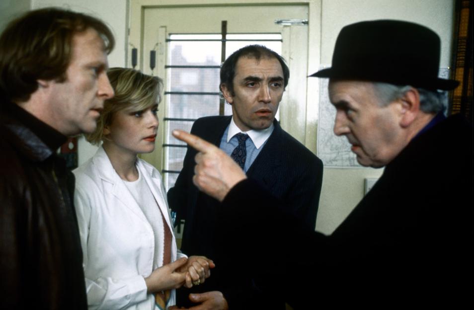 Still from the TV show *Minder*, featuring Dennis Waterman, Nicola Cowper, and George Cole.
