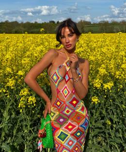 Woman in colorful crochet dress in a field of yellow flowers.