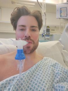 Man in hospital gown using a nebulizer.