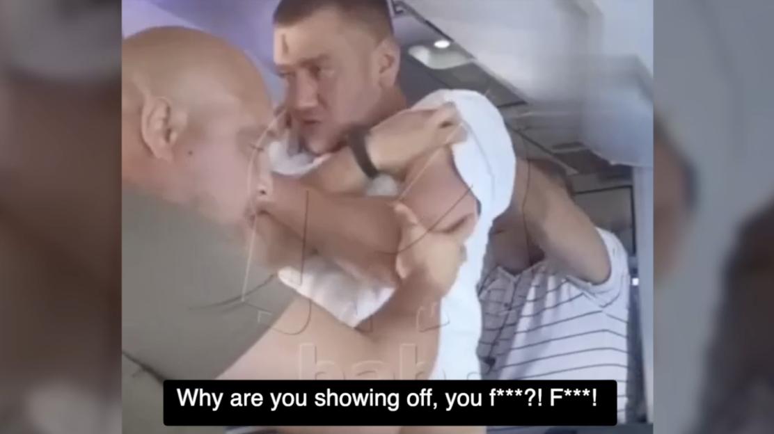 Male passengers subduing a disruptive passenger on an airplane.