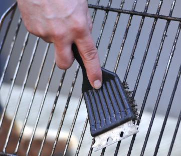 Hand cleaning a grill grate with a brush.