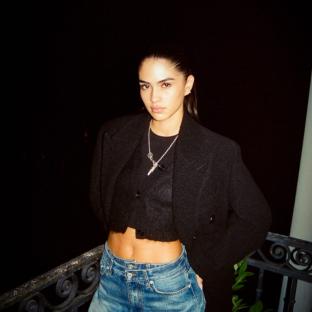 Woman in black cardigan and jeans at night.