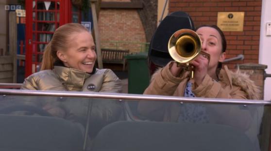 Natalie Cassidy and Patsy Palmer, as their EastEnders characters Sonia and Bianca Fowler, in a car; Sonia is laughing, and Bianca plays a trumpet.