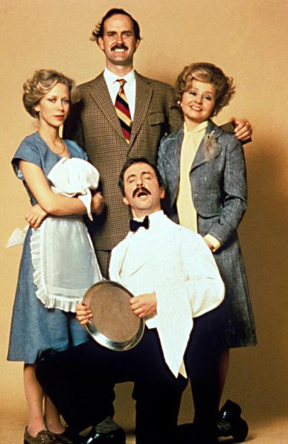A group of people posing for a picture, including a man in a tuxedo holding a tray