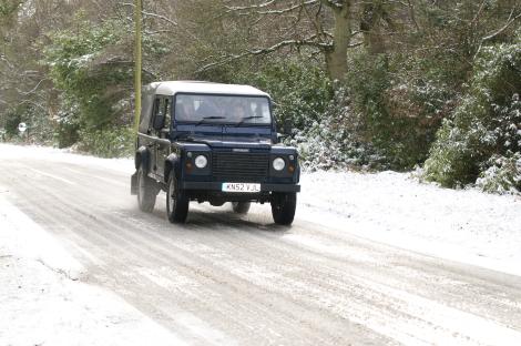 Land Rover Defender driving on a snowy road.