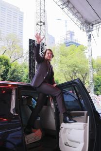 Tom Cruise exiting a car and waving.