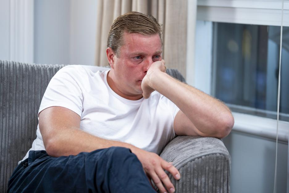 Thomas Skinner looking distressed while sitting on a couch.