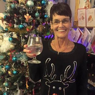 Catherine Flynn holding a glass of water in front of a Christmas tree.