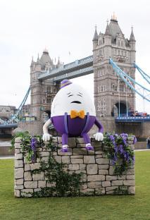 Humpty Dumpty figure sitting on a wall with Tower Bridge in the background.