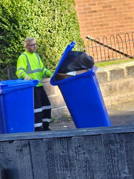 Aidan Edwards emptying a blue recycling bin.