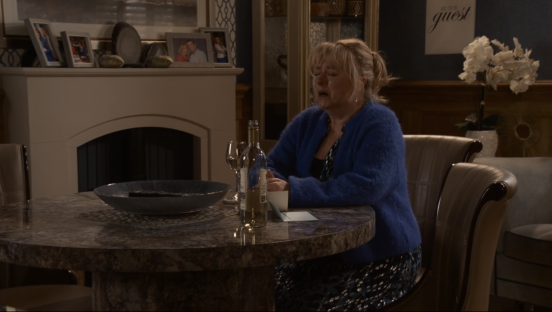 A woman sits at a table crying.