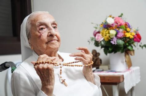 Elderly nun holding rosary beads.