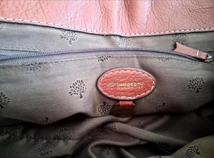 Inside of a Mulberry handbag showing the brand's logo.