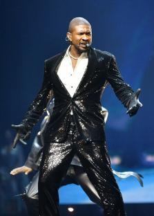 Usher performing on stage in a sequined suit.