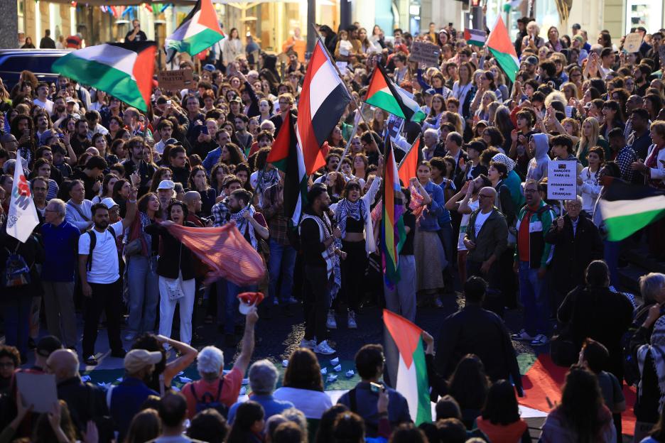 Protesters gathered in Porto, Portugal, waving Palestinian flags and holding signs.