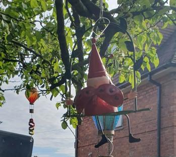Gnome hanging from tree in garden.